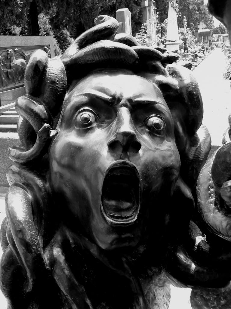 Close-up of a dramatic Medusa sculpture with expressive face in black and white.