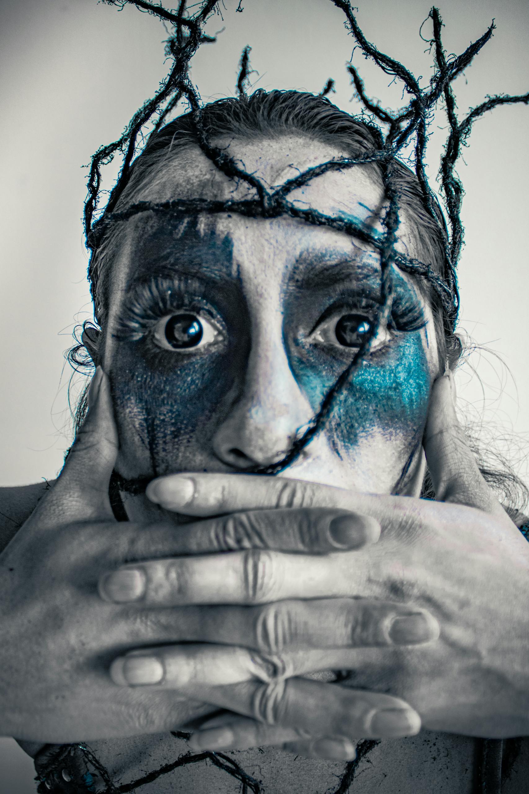 Creative horror makeup on a woman with twigs and blue face paint.